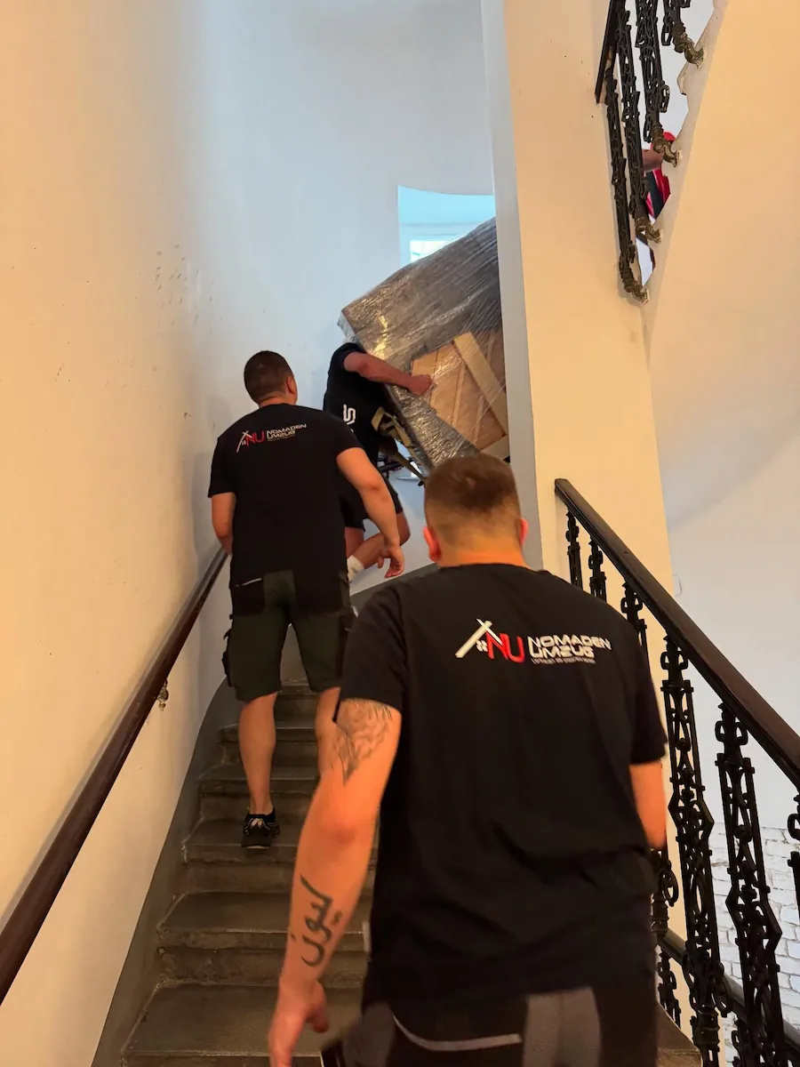 Nomaden Umzug Möbelpacker beim Möbeltransport auf einer Treppe im Wiener Althaus.
