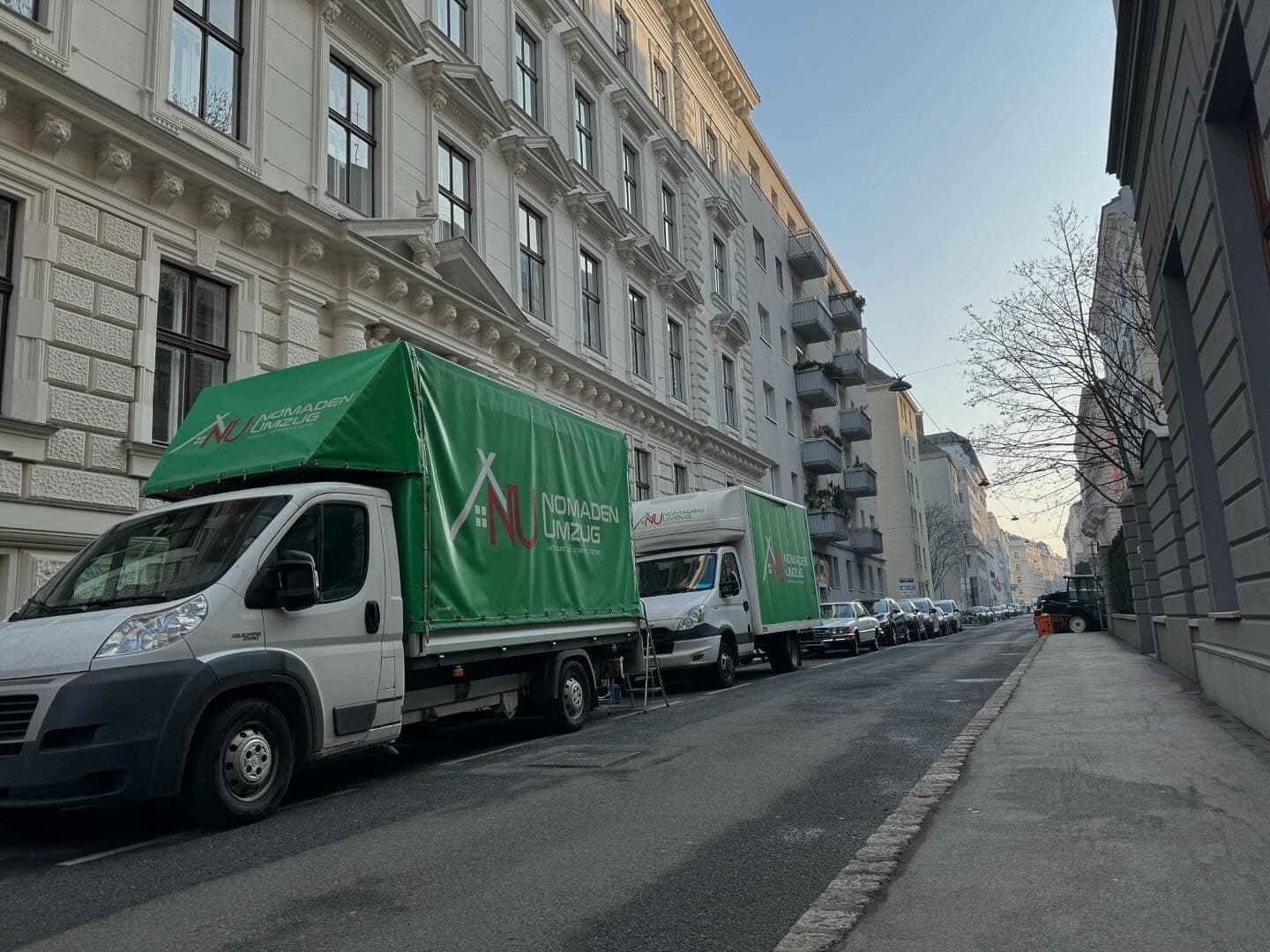 Nomaden Umzug Wien – Zwei Umzugs-LKWs mit Firmenbranding auf Wiener Wohnstraße